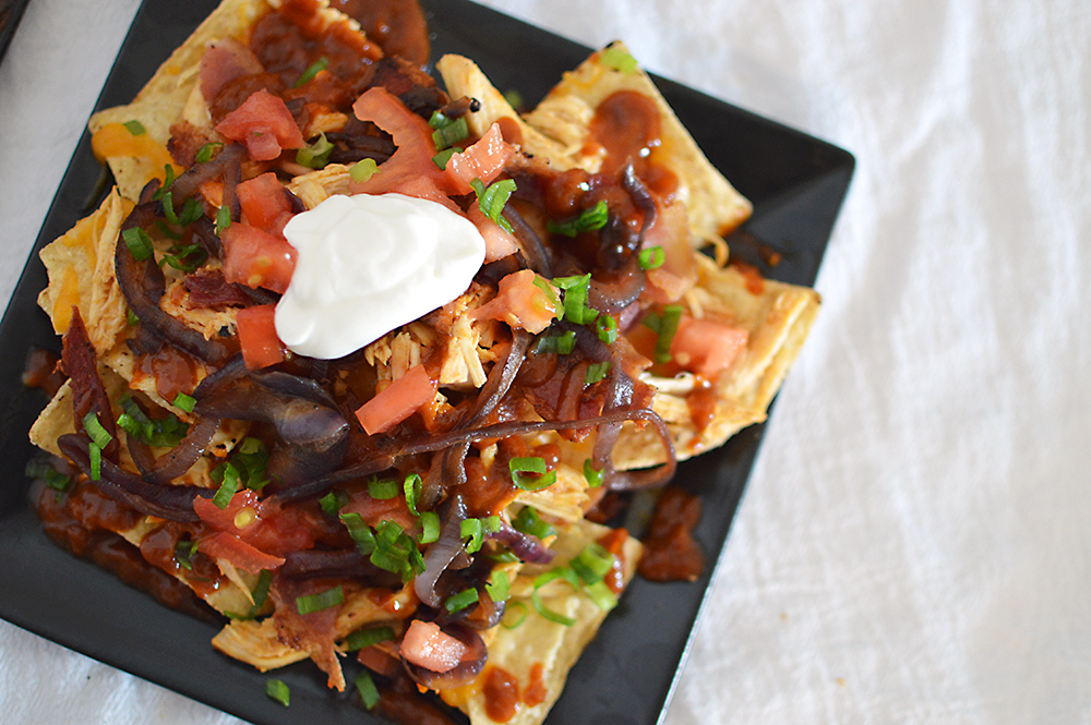 The homemade root beer barbecue sauce is what MAKES this dish! Warm BBQ chicken, cheese, caramelized onions and bacon top these sweet, semi-spicy nachos. Garnish with tomatoes, green onions, and sour cream if you want to max out the flavor! Recipe from thatquareplate.com